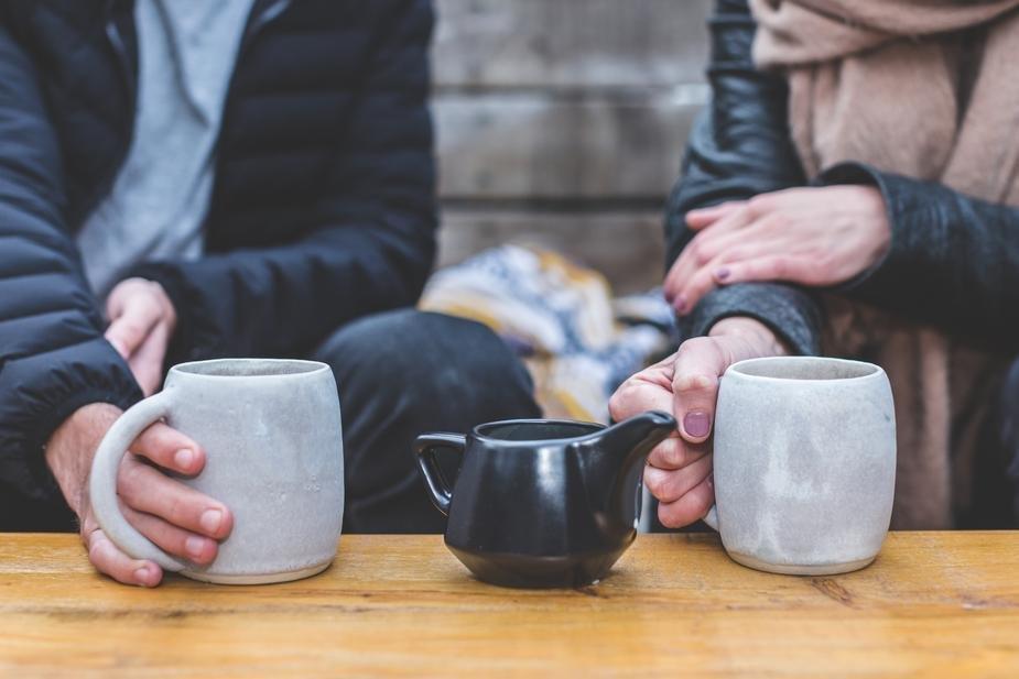 2 people having a conversation with mugs of coffee