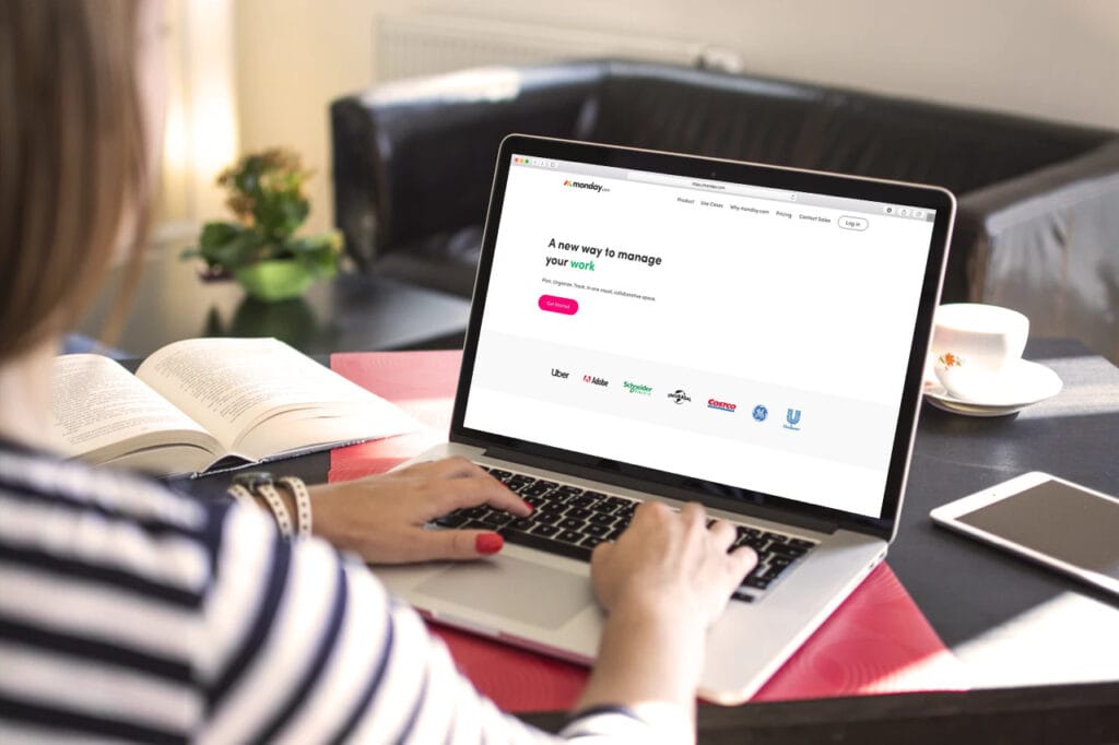 A person sitting at a table using a laptop with monday.com on the screen