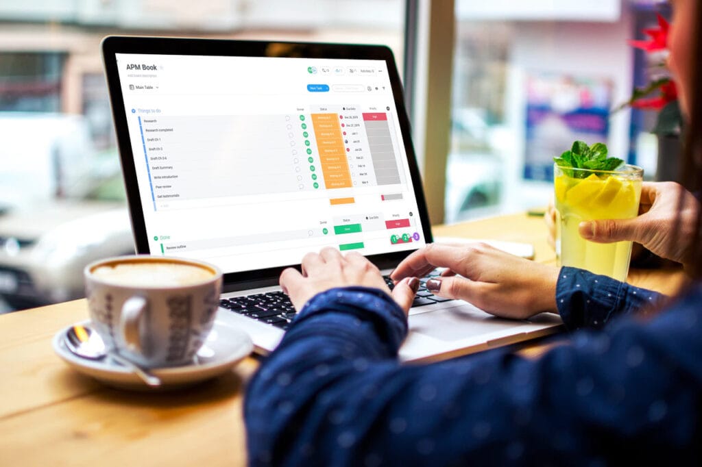 A person sitting at a table using a laptop with a coffee cup