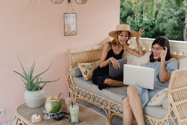 two women sitting casually holding laptops