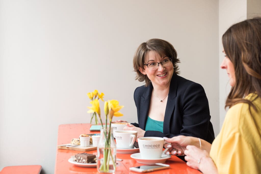 Elizabeth Harrin sitting at a table with a vase of daffodils