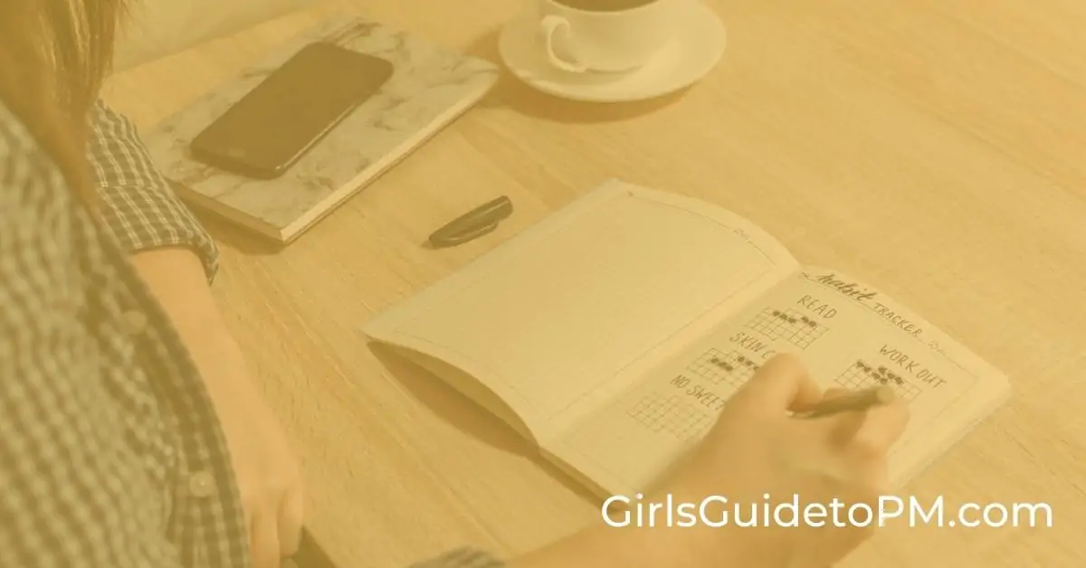 A person using a bullet journal at a table, with a cup of tea