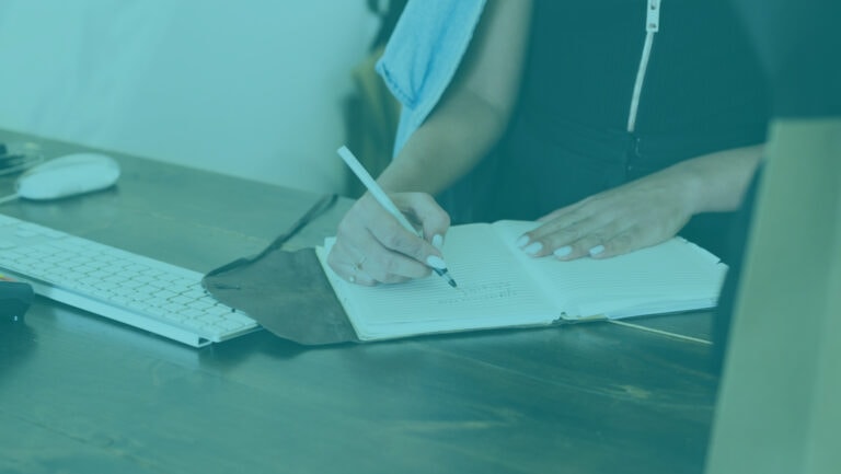 A person writing in a notebook on a desk